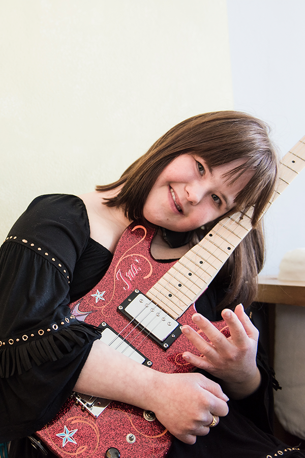 Resonaarin oppilas nojaa kitaraan ja hymyilee
